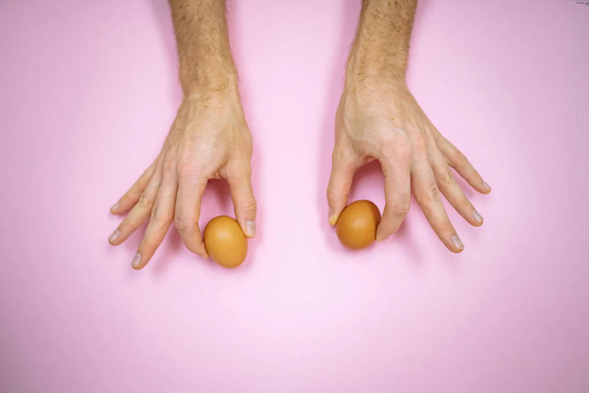 Two hands cupping a pair of fresh brown eggs